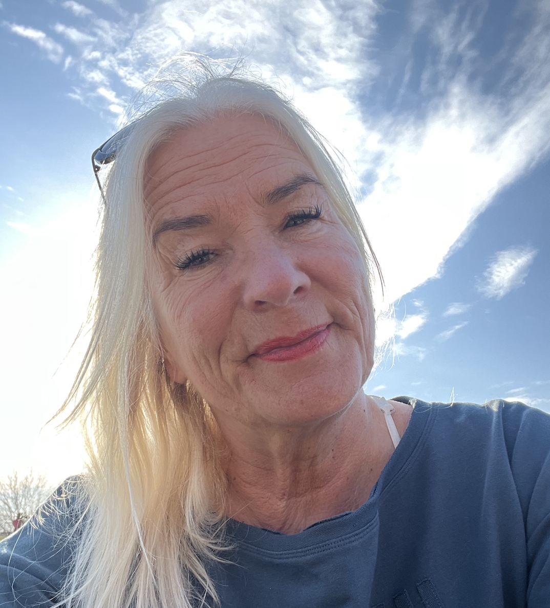 Christina tittar ner i kameran, ovanför henne är himlen härligt blå.