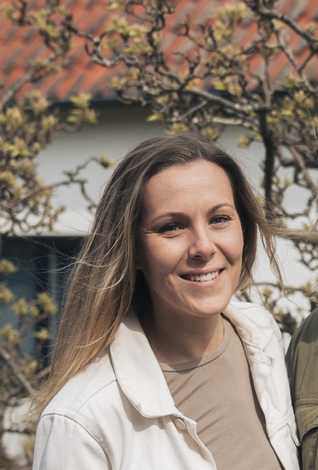 Maja ler mot kameran, i bakgrunden har träden börjat få knoppar.